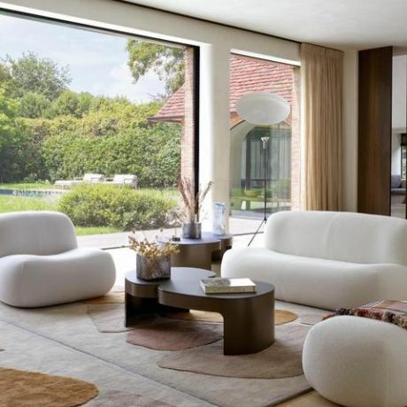 غرفة معيشة ligne roset مع أريكة pukka وكرسي بذراعين ومسند أقدام وطاولة وسجادة